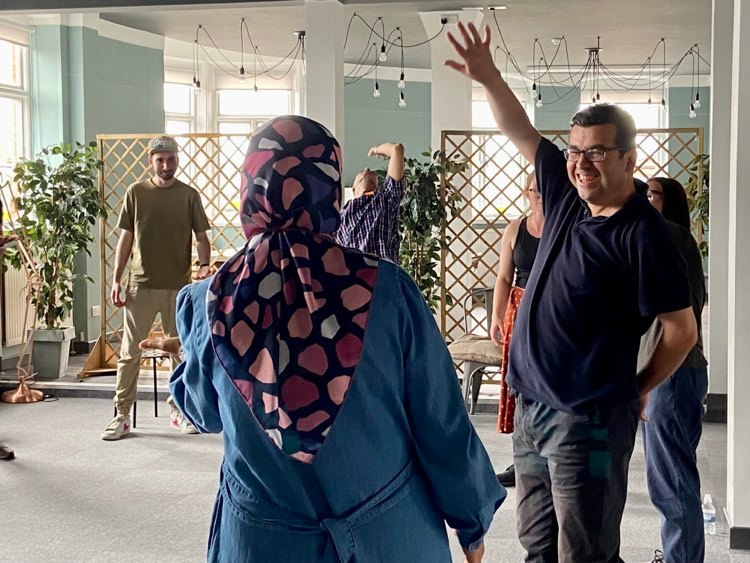 group of people standing in a semi-circle and one man smiling and raising his hand