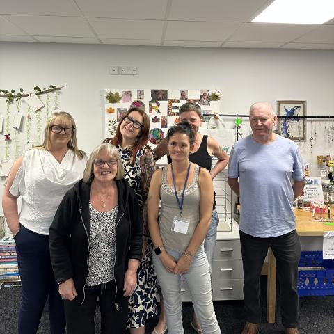 6 people, standing in an office, smiling at the camers