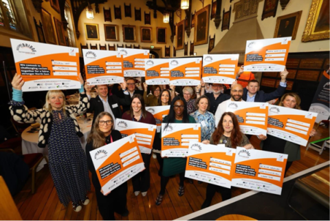 Taking Action - Group of people hold up the pledge