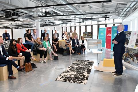 A group of people sit watching a presentation in a new bright and functional office space at One Strawberry Lane