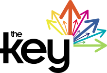 The Key written in black font with 12 arrows shooting off from the Y in 12 different colours