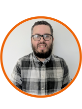 A head and shoulders shot of Daniel, he has short dark hair and a beard, glasses, and is wearing a grey checked shirt