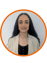 A head and shoulders shot of Mehru-Nisa, she has long dark hair and is wearing a black top with a thin cream cardigan