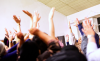 A group of dancers shown from behind, raising their hands in the air
